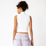 A model wears a sleeveless white mockneck tank top in white, paired with light purple sweat shorts - back view.