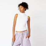 A model wears a sleeveless white mockneck tank top in white - front view.