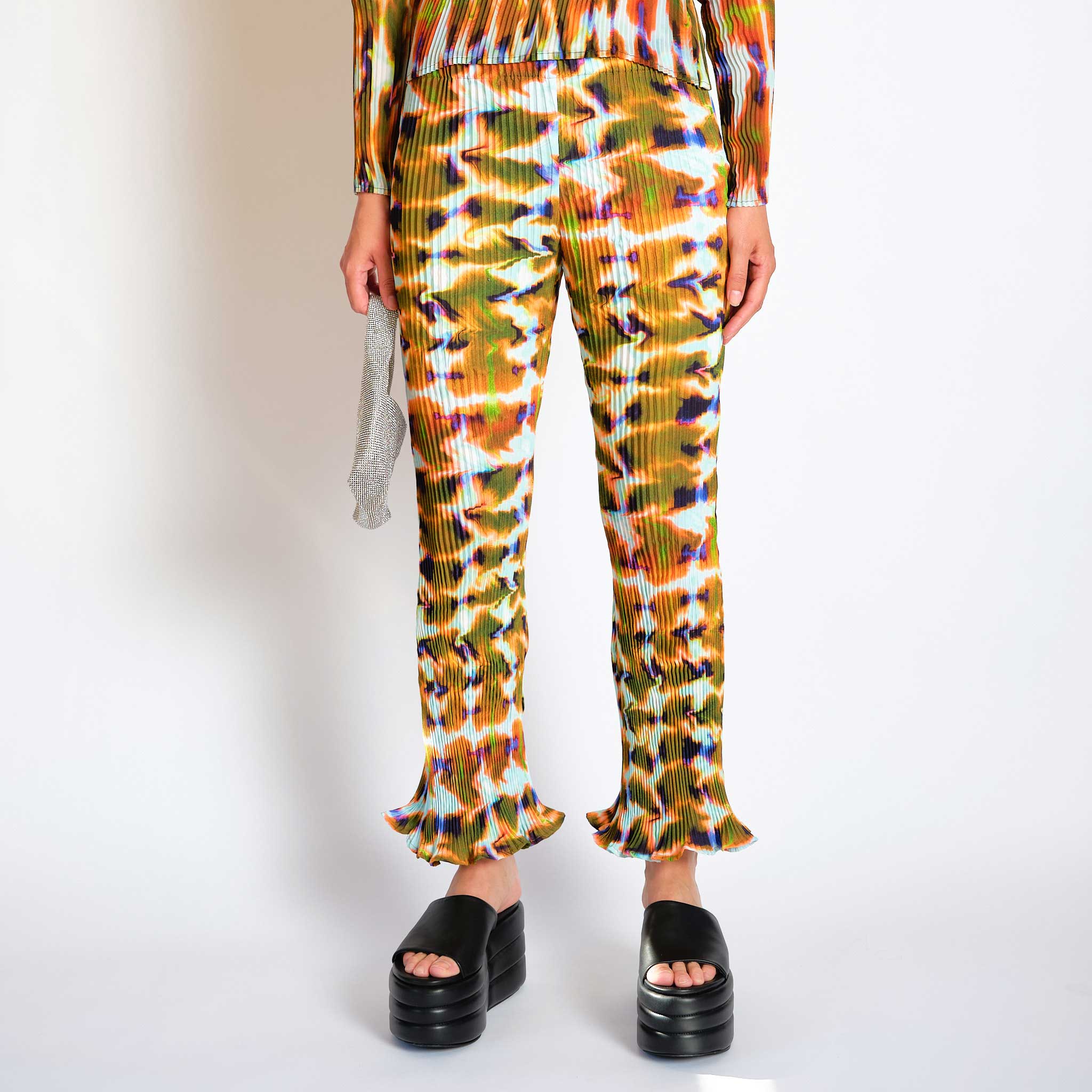 A model wears the Rose Trousers in the orange and green repeating Wallace graphic - front view.