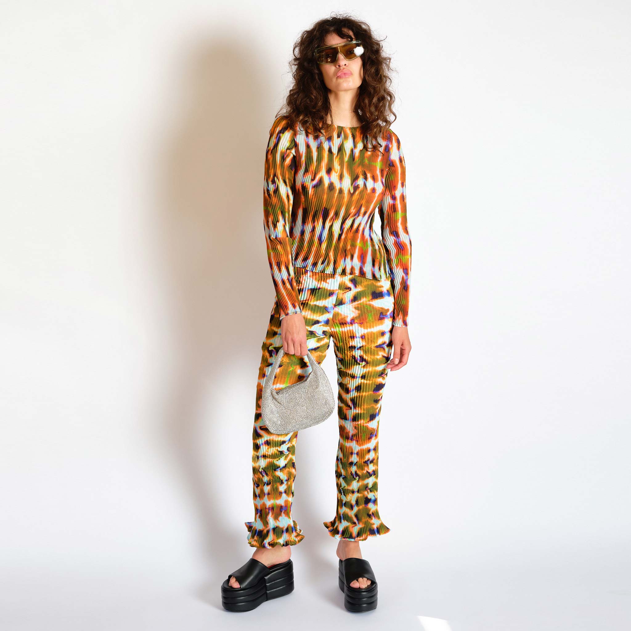 A model wears the Rose Trousers in the orange and green repeating Wallace graphic - full outfit view.