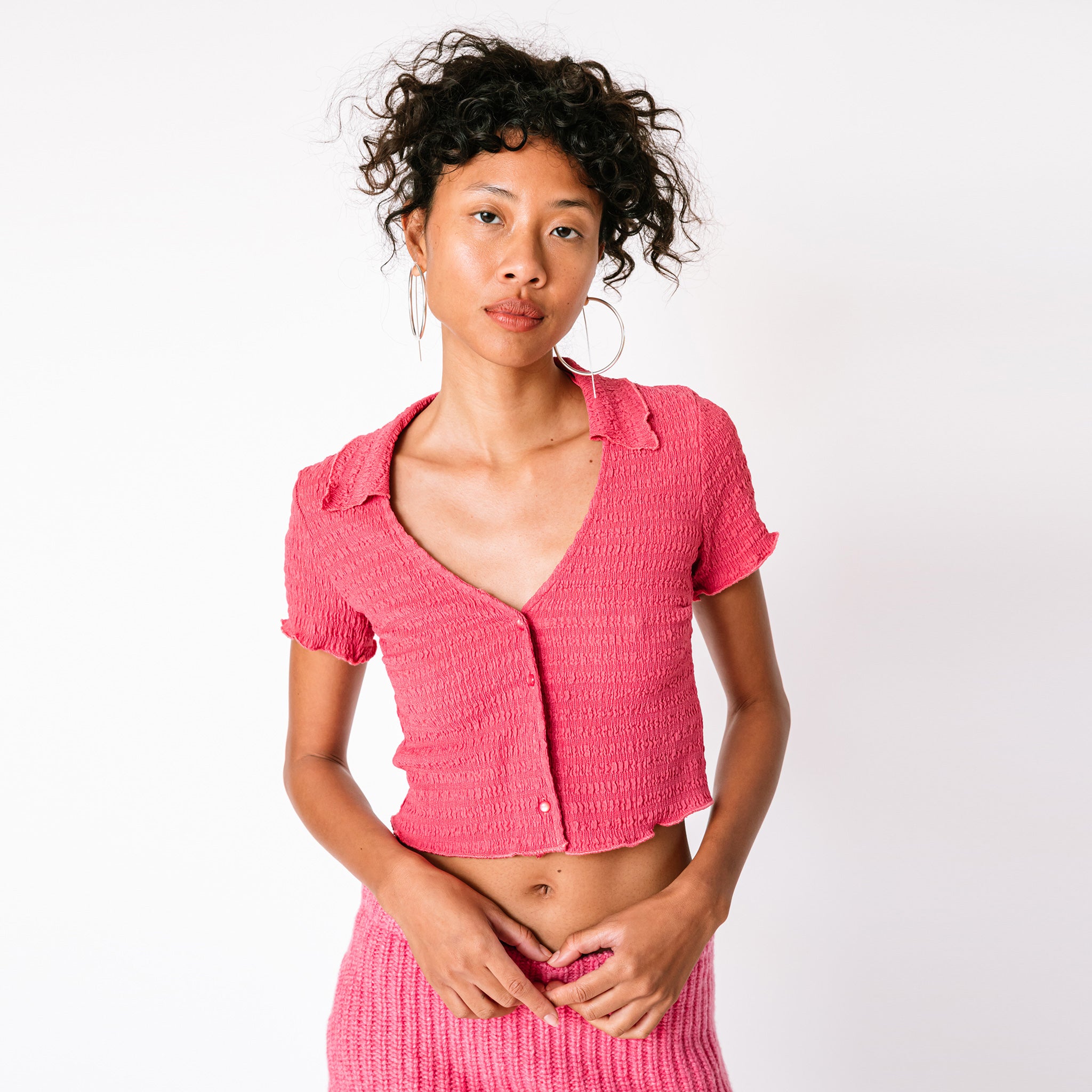 A model wears Misc Etc's pink ruched polo top in dark rose, paired with a matching pink mini skirt, closer view.