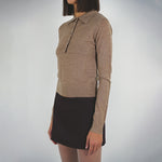 Front half body photo of model wearing the Seek Sweater paired with a dark brown mini skirt.