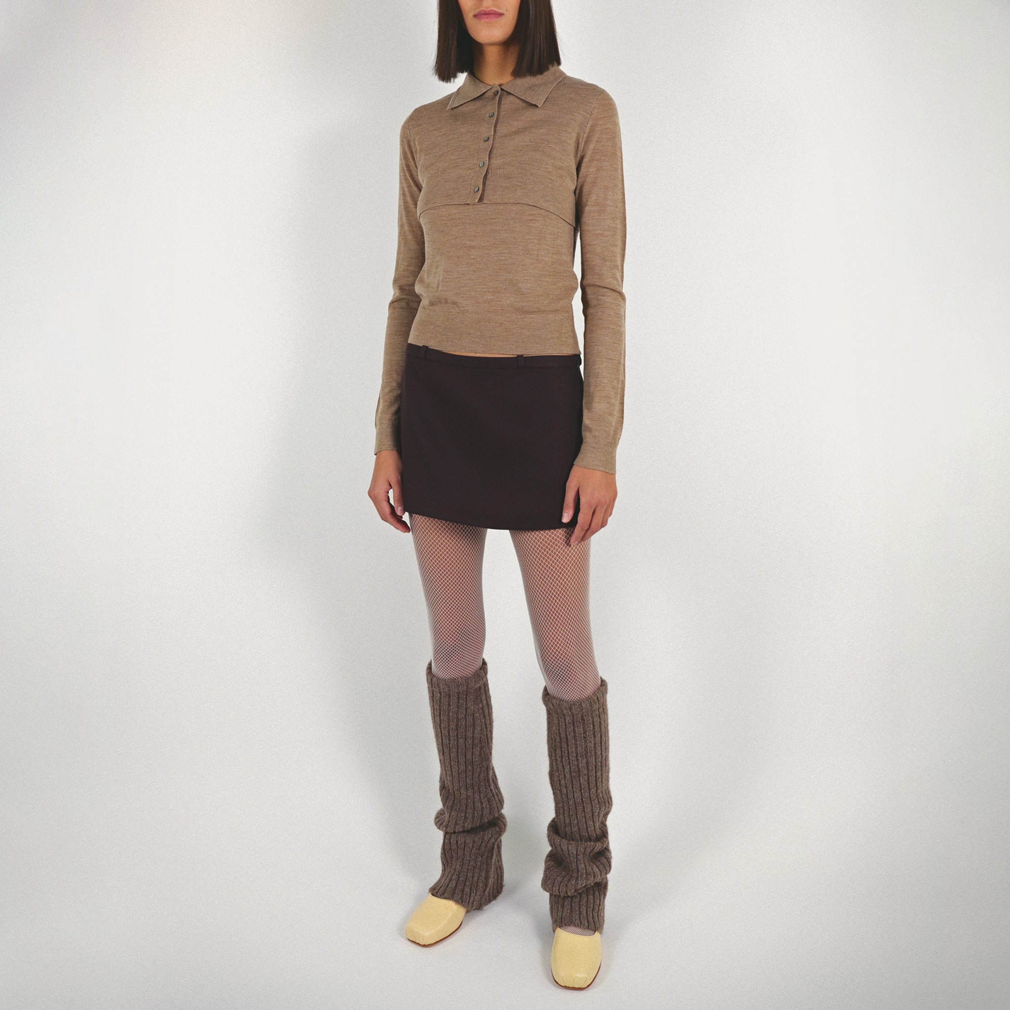 Front full body photo of model wearing the Seek Sweater paired with a dark brown mini skirt and yellow ballet flats.