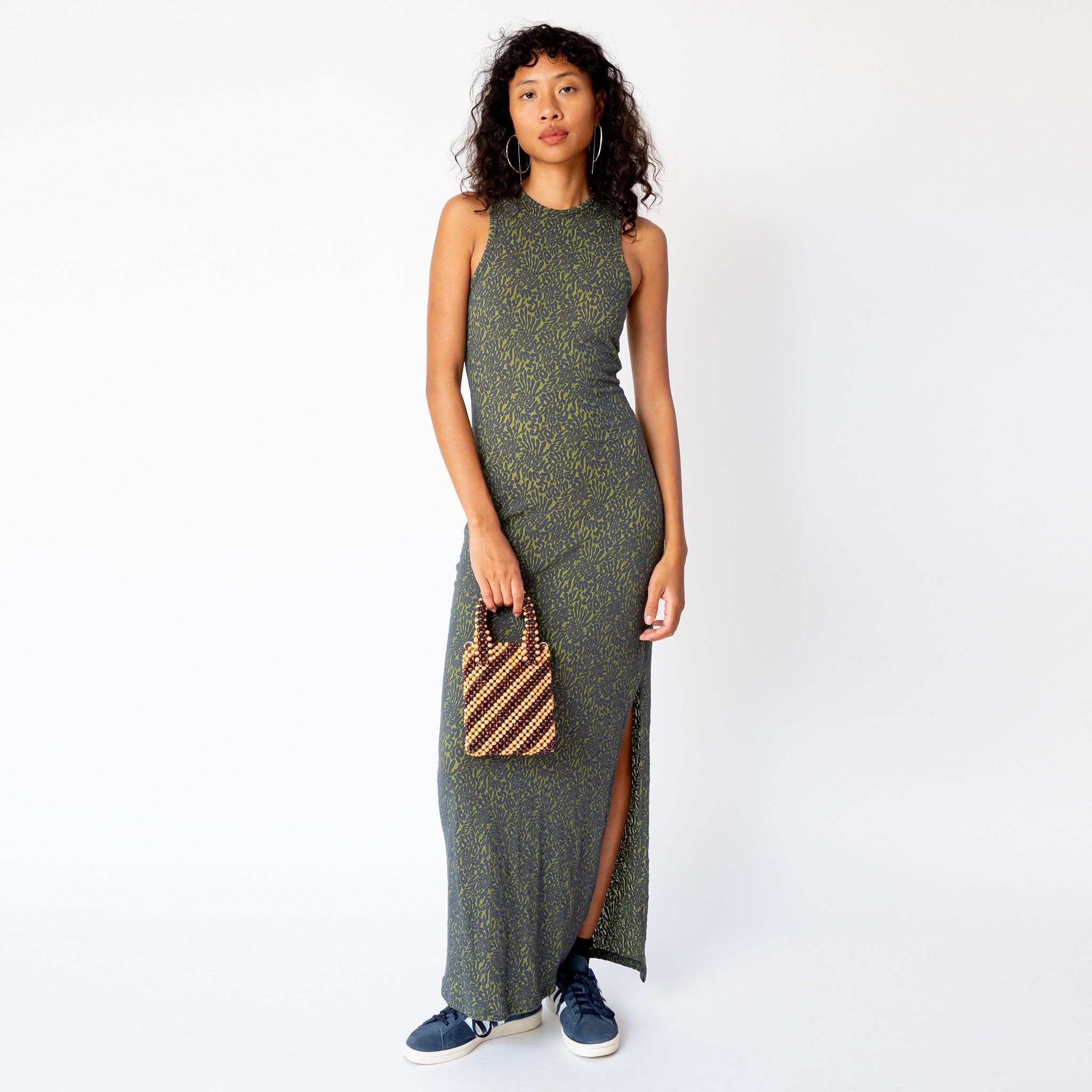 A model wears the form-fitting Shrunk Dress by Eckhaus Latta, a sleeveless full length casual dress in a green printed pattern, full outfit view.