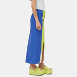 Close half body photo of model wearing the Simi Skirt - a full length denim skirt painted in color blocks of chartreuse, blue, and white - side view.