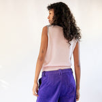 A model wears the frost gray sleeveless polo top with contrasting navy blue collar and gold button hardware - back view.