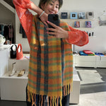Geraldine smiles wearing the yellow and orange checked Sliced wool scarf.