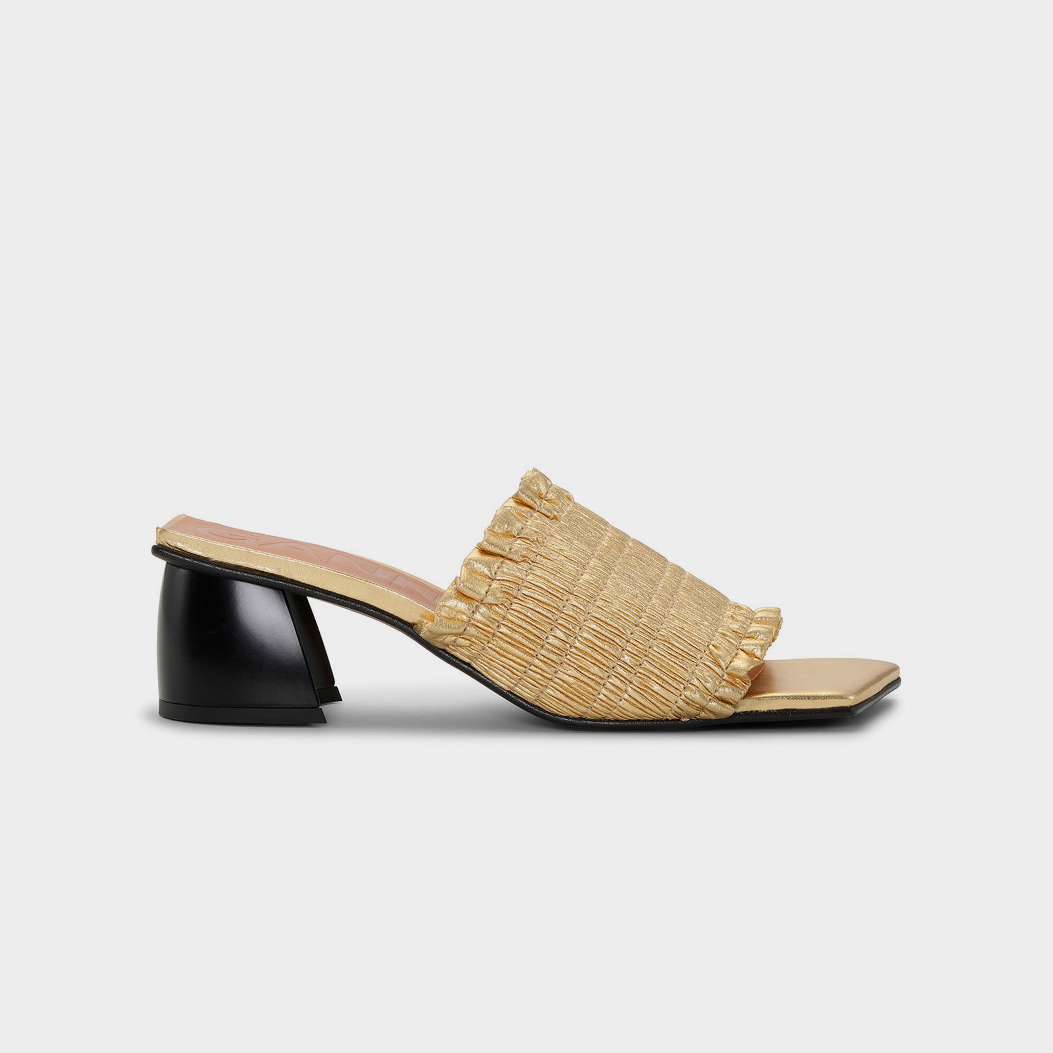 Gold heeled slide with black block heel, square toe, and gold upper, with smocked gold vamp - side view.