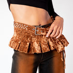 Detailed close up of a model wearing the velvet Star Pleated Belt in bark brown, an expressive belt with studded metal stars along the waistband and descending pleated micro skirt.