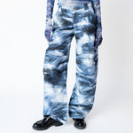 A model wears the blue and white graphic dolphin printed, wide leg Stomp Pant by Collina Strada with matching mesh top and gloves - front close up.