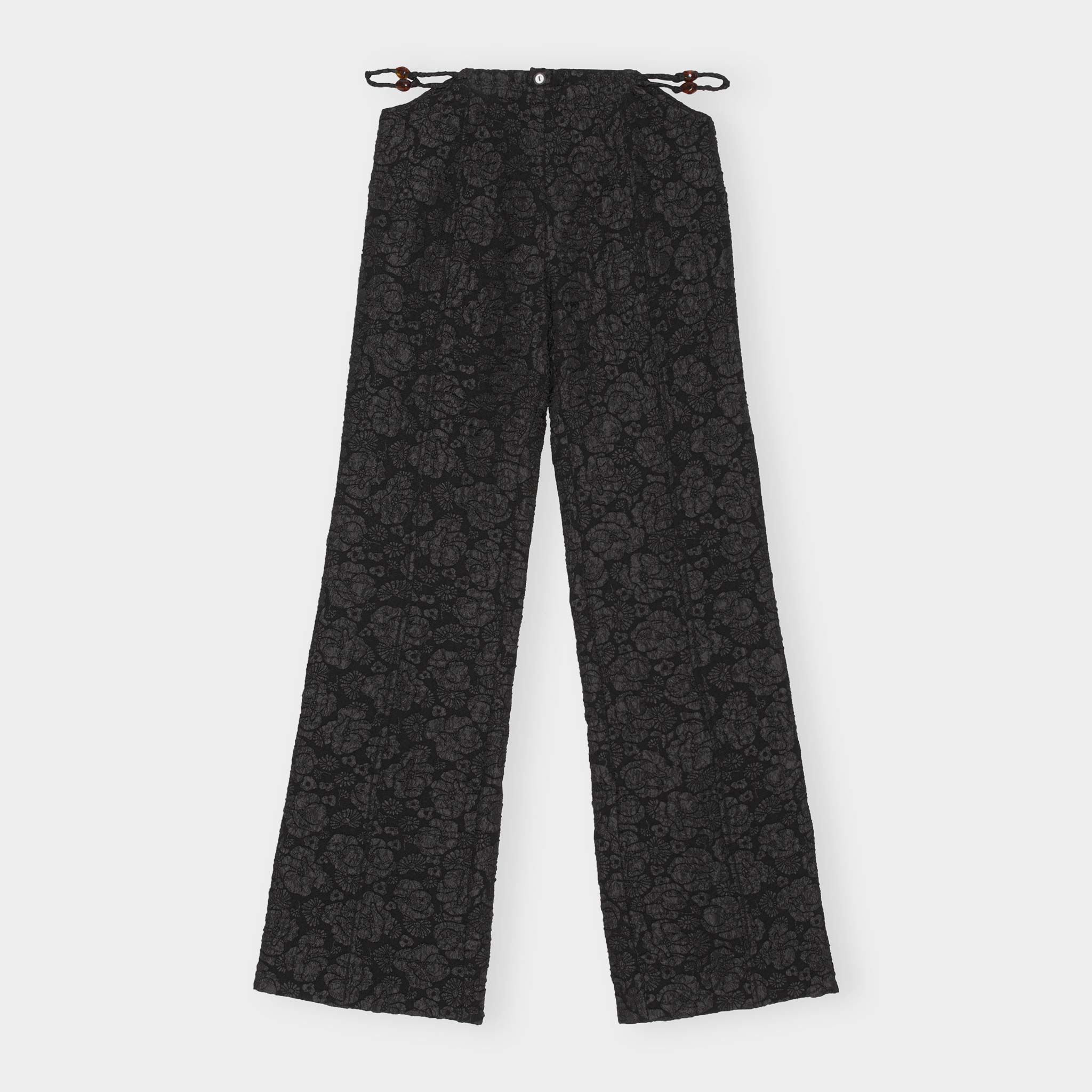 Black floral jacquard trousers with a slightly flared leg and featuring side waist cutout details exposing a thin twisted rope belt - front view.