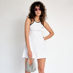 A model wears the white tennis court dress by Marine Serre - front view.