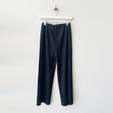 Hanger photo of black Pleats Please pants with a full straight leg, thicker pleating, and hidden side pockets.