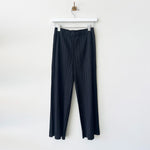 Hanger photo of black Pleats Please pants with a full straight leg, thicker pleating, and hidden side pockets.