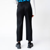 A model wearing the black Thicker Bottoms 2 pleated trousers by Pleats Please, back view.