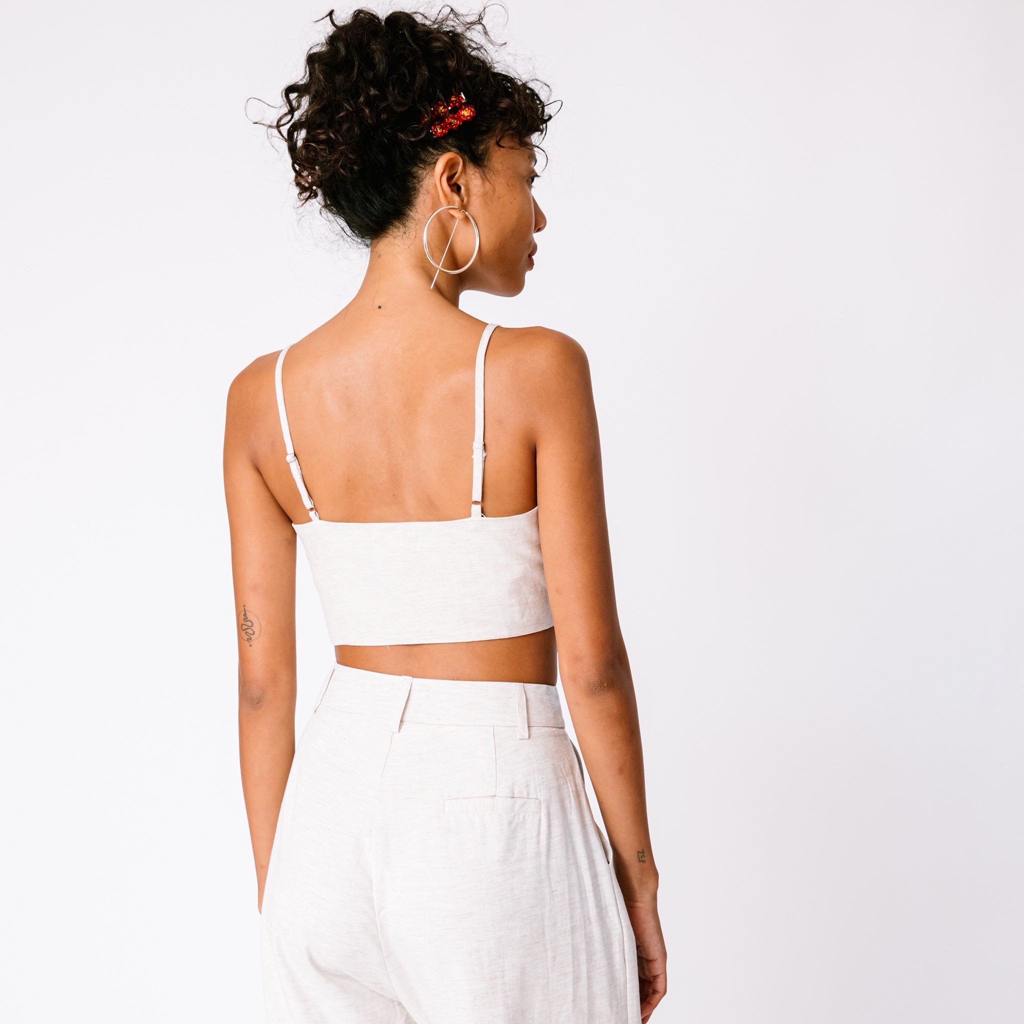 A model wears the Tie Cami Top and large silver hoop earrings, back view.