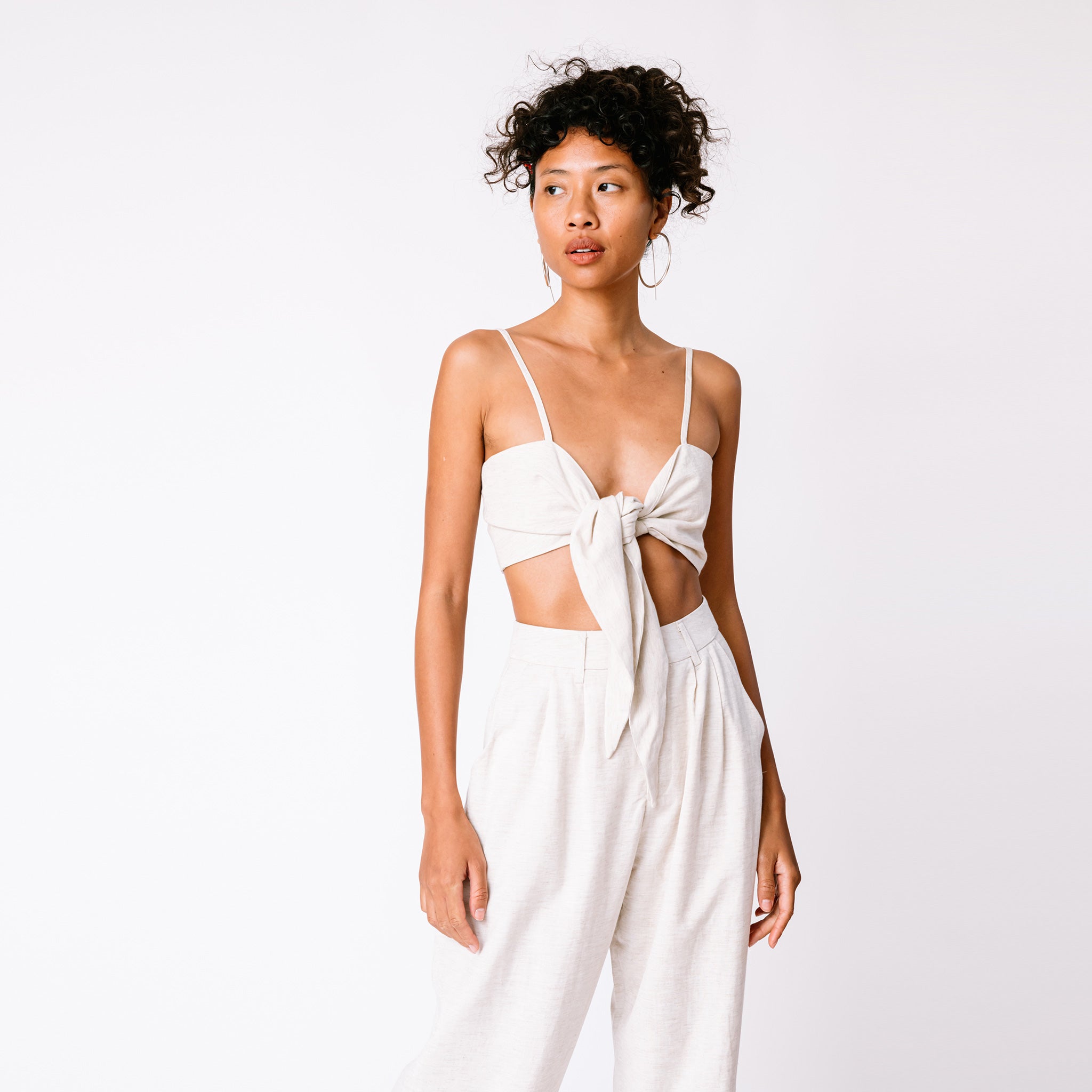 A model wears the Tie Cami Top paired with matching linen pants and large silver hoop earrings.