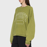 Side photo of model wearing a oversized stussy crewneck sweatshirt in a light green color.