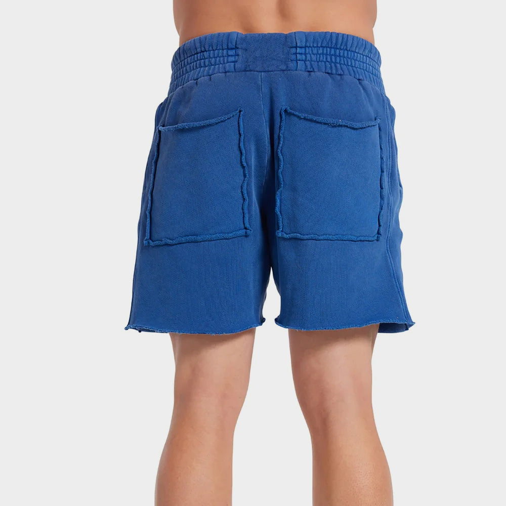 Back photo  of a male model wears the electric blue cotton Yacht Short by Les Tien, featuring a wide elastic waistband and long white waist ties and side pockets.