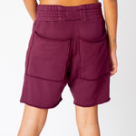 A model wears the merlot-red pigment dyed Yacht sweat shorts by Les Tien - back view of the rear pockets with unfinished edges.