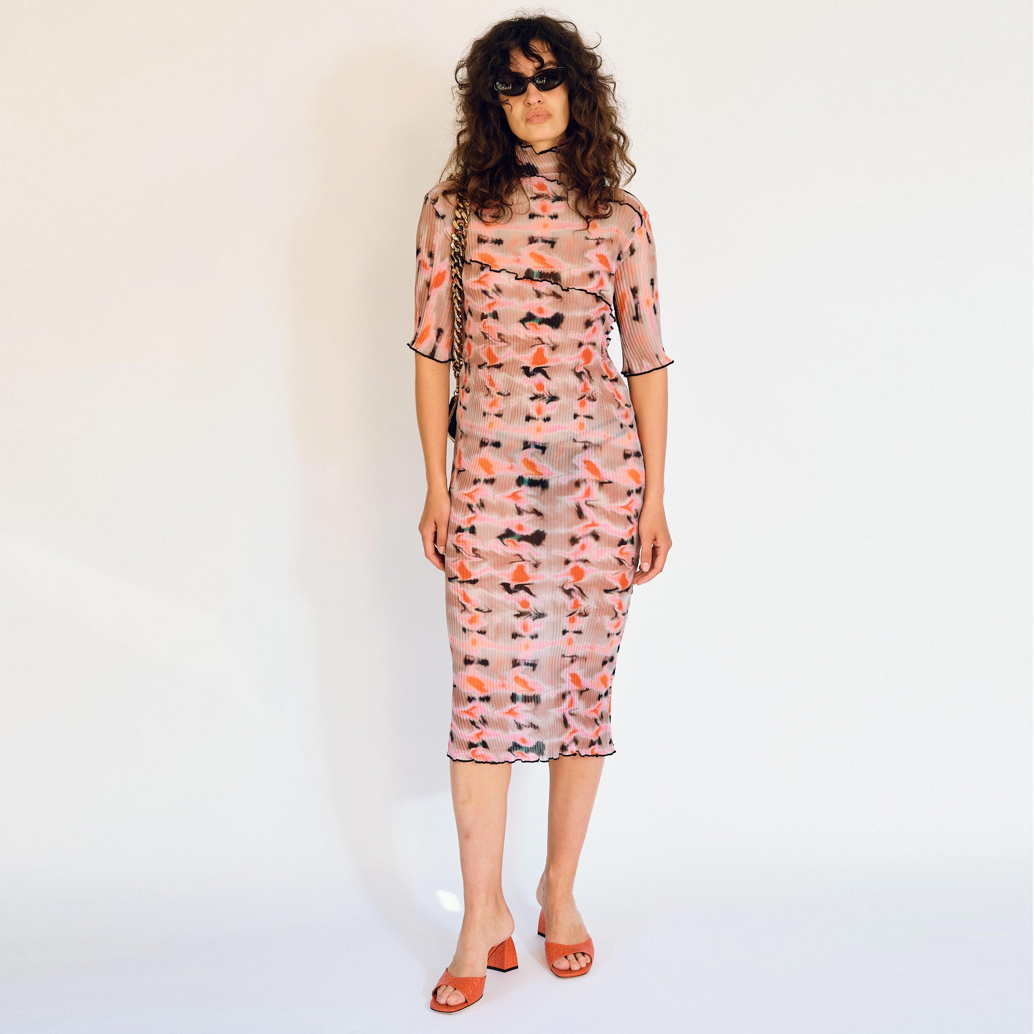 A model wears the graphic pleated Rainer dress in the pink Wallace color way, front view.