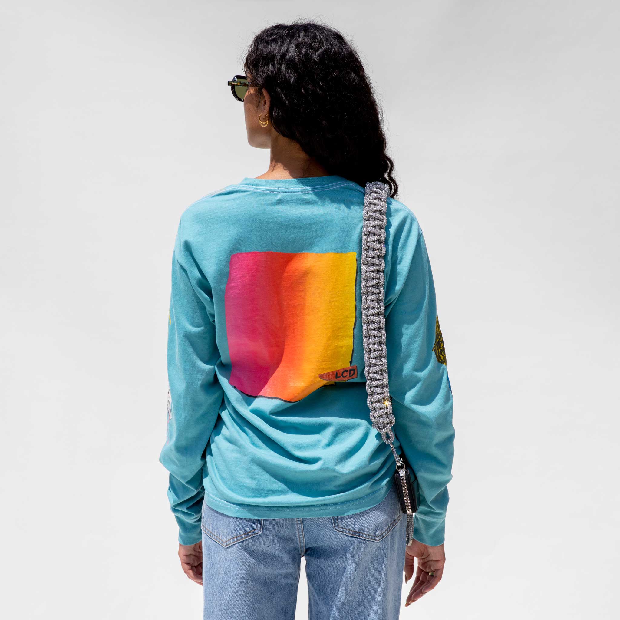 Back detail photo of model wearing the Vintage Washed LCD10 Long Sleeve Graphic Tee - Teal. 