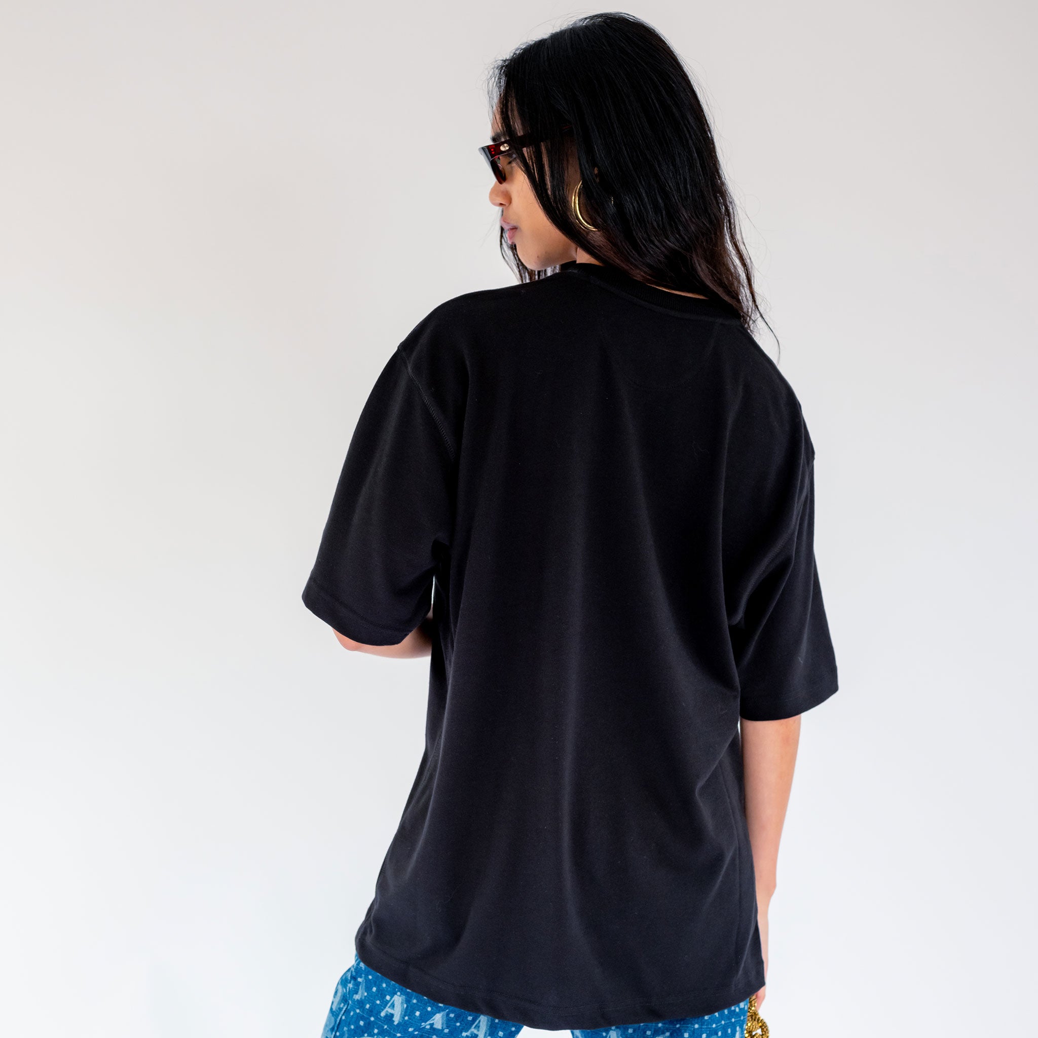 Back half body photo of model wearing the Artefact Tee - Black.