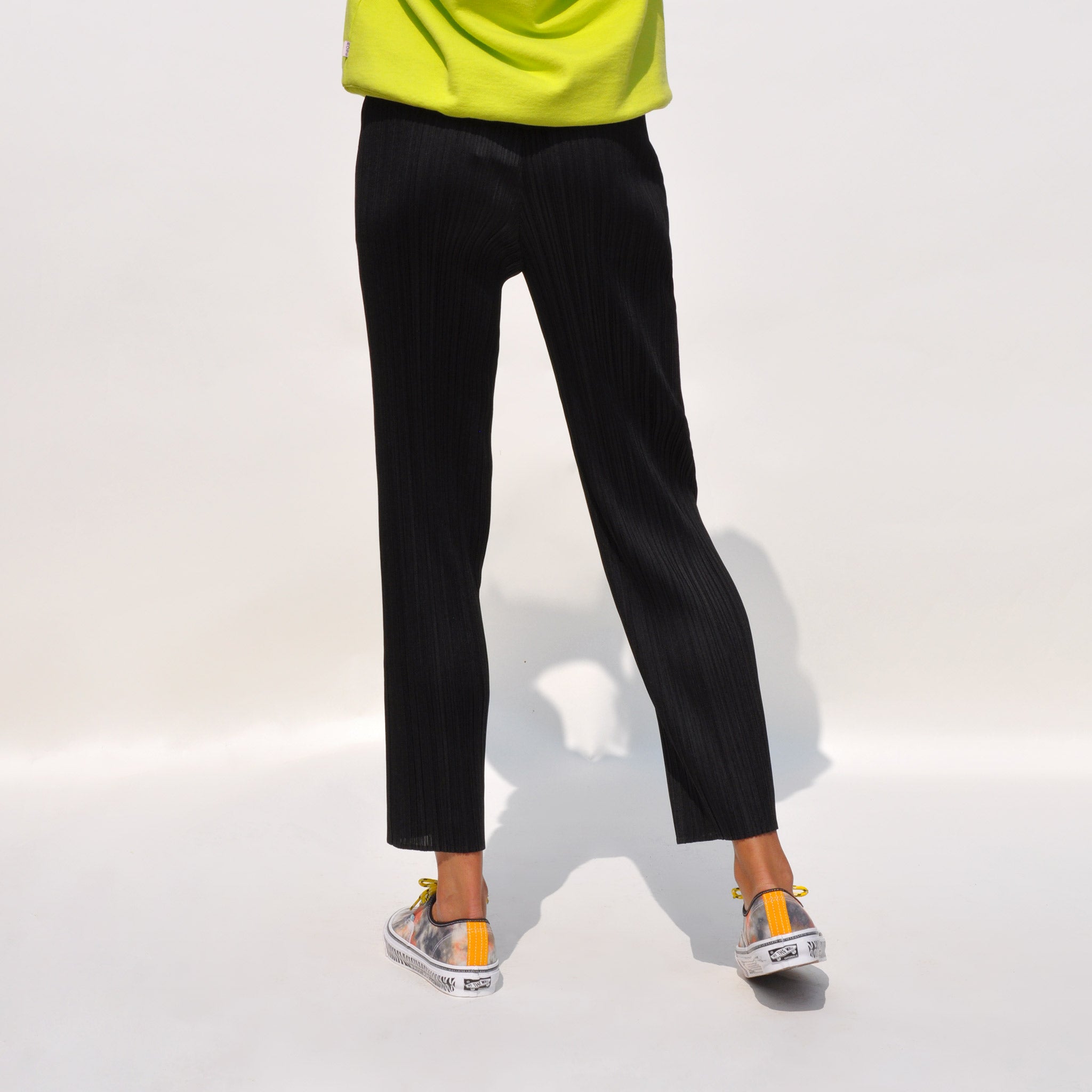 Close up back shot of model wearing Basics Slim Pants in black by Pleats Please.