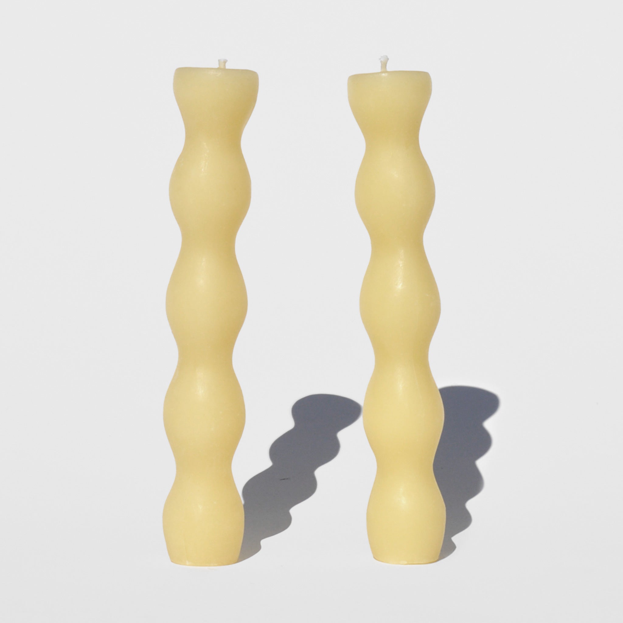Photo of a pair of natural beeswax candles with a wavy columned shape.