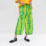 Close up image of a model wearing the chef pants by meals in watermelon. these oversized Cargo pants are green and yellow tie-dye. Like the outside of a watermelon.