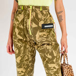Detailed close up photo of a model wearing the unisex Aries Crinkle Camo Walking Trouser, with fluorescent yellow zipper detail and belt loops.