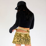 Back view of a model wearing the green camo Aries mini skirt with looping belt detail.