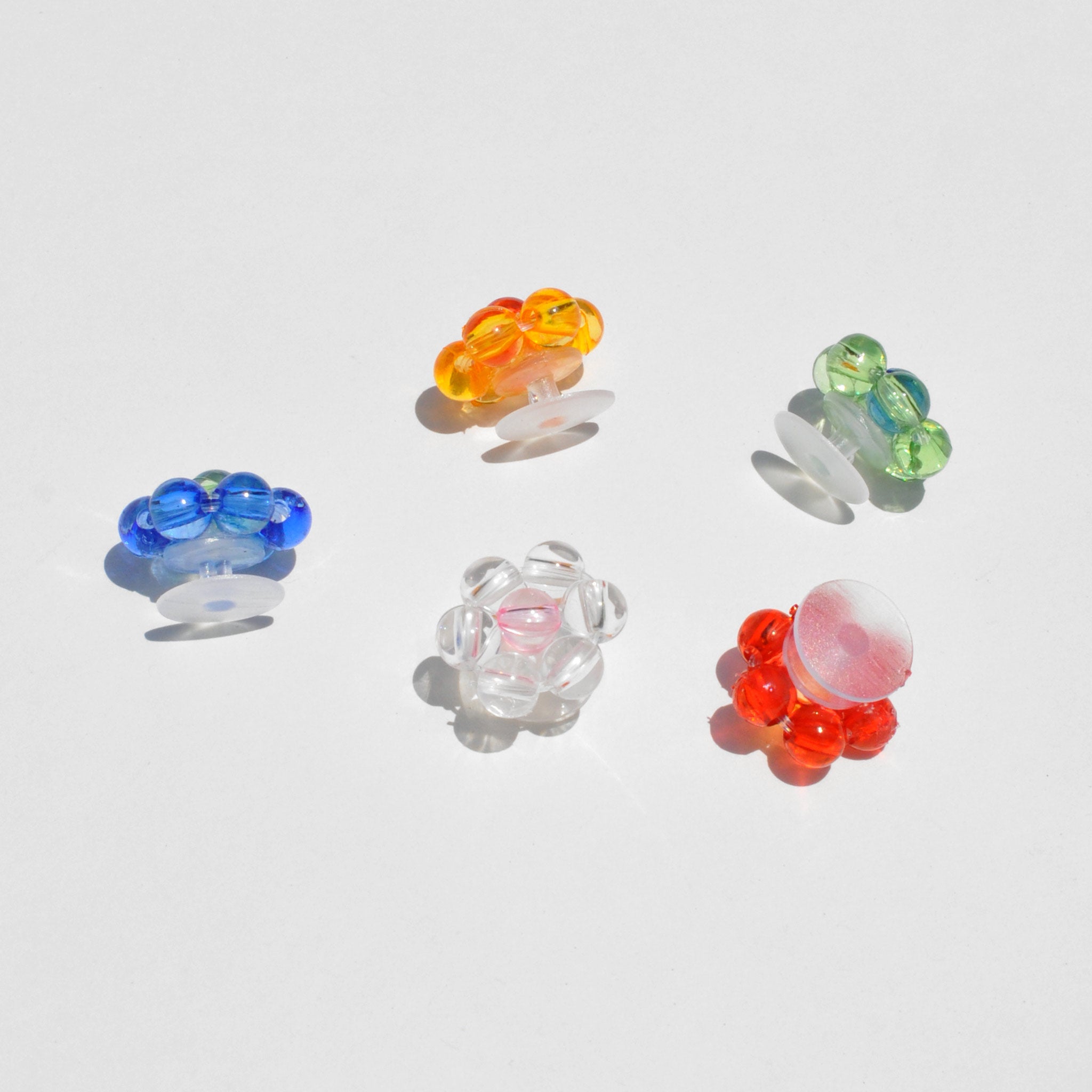 Photo displays croc charms available at LCD. Flower shaped charms of various colors on white backdrop.