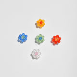 Photo displays croc charms available at LCD. Flower shaped charms of various colors on white backdrop.