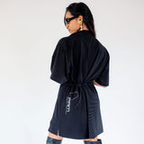 Back half body photo of model wearing the Ellipse Asymmetrical Zip Dress - Black.