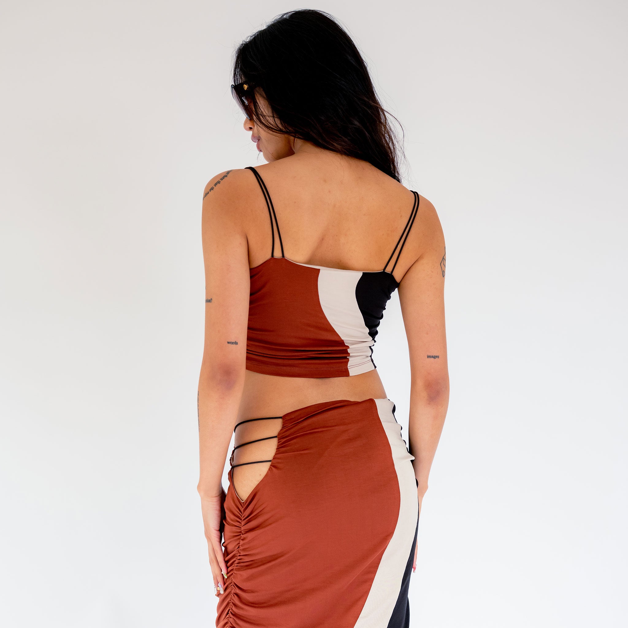 Back half body photo of model wearing the Elshadai Top - Black/Rust/Beige.