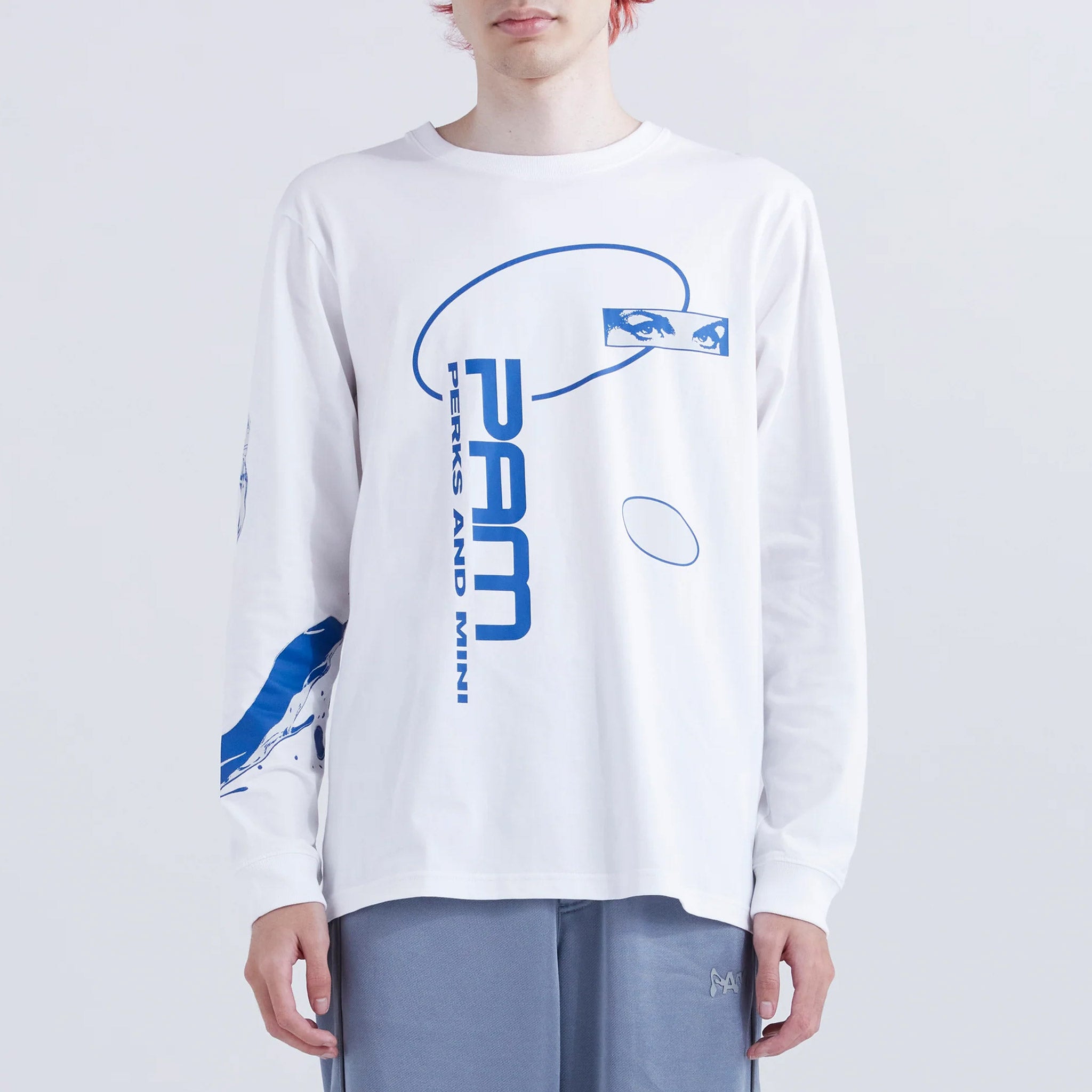 A model wears a white longsleeve cotton graphic tee with a blue PAM logo graphic printed on the front and a liquid graphic on the right sleeve.