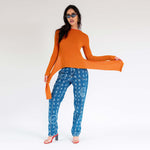 Full outfit photo of a model wearing the orange fluted sweater by Eckhaus Latta with hanging side tails.