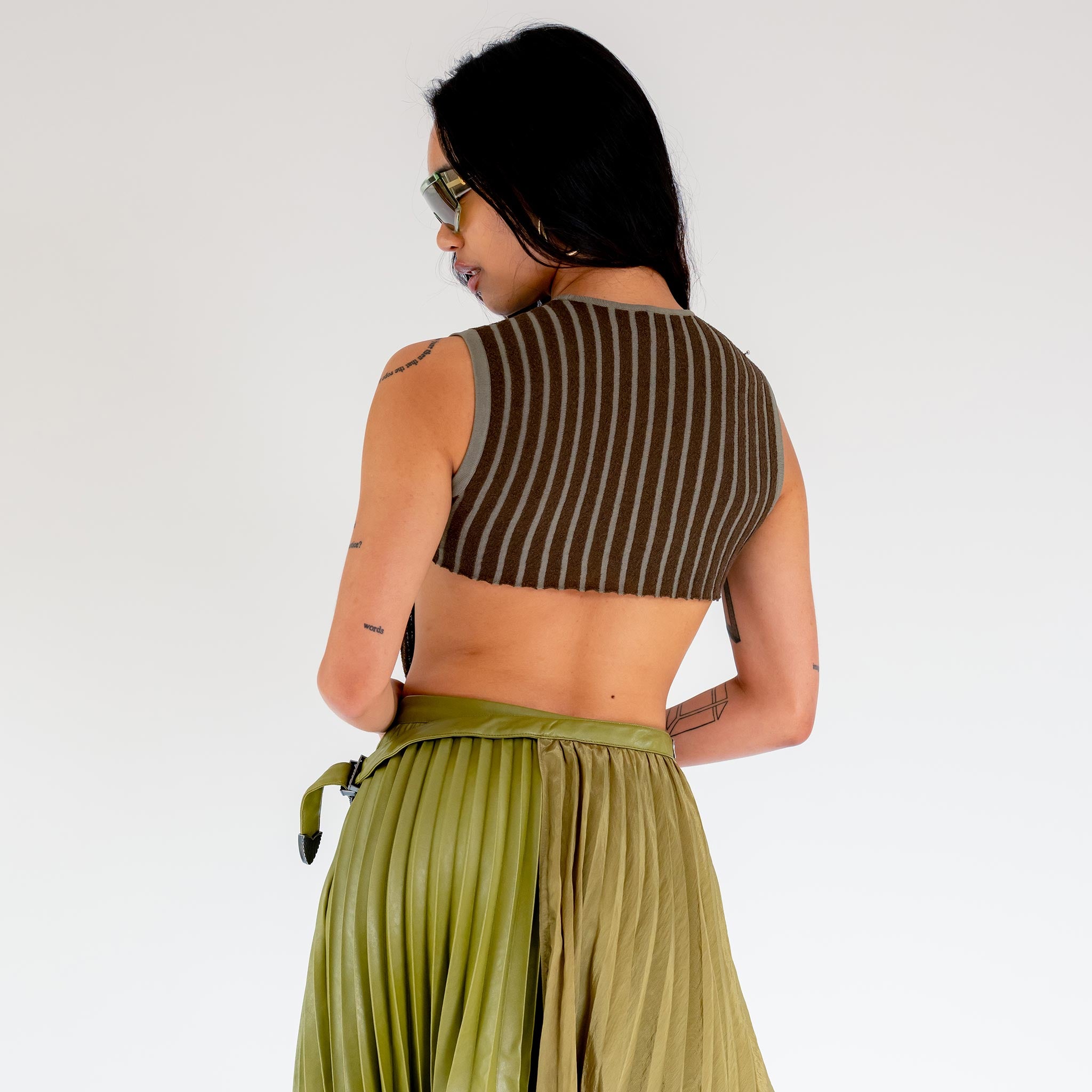 Back photo of model wearing the Fluted Tank - Lichen. a cropped ribbed knit tank with cutout back detail.