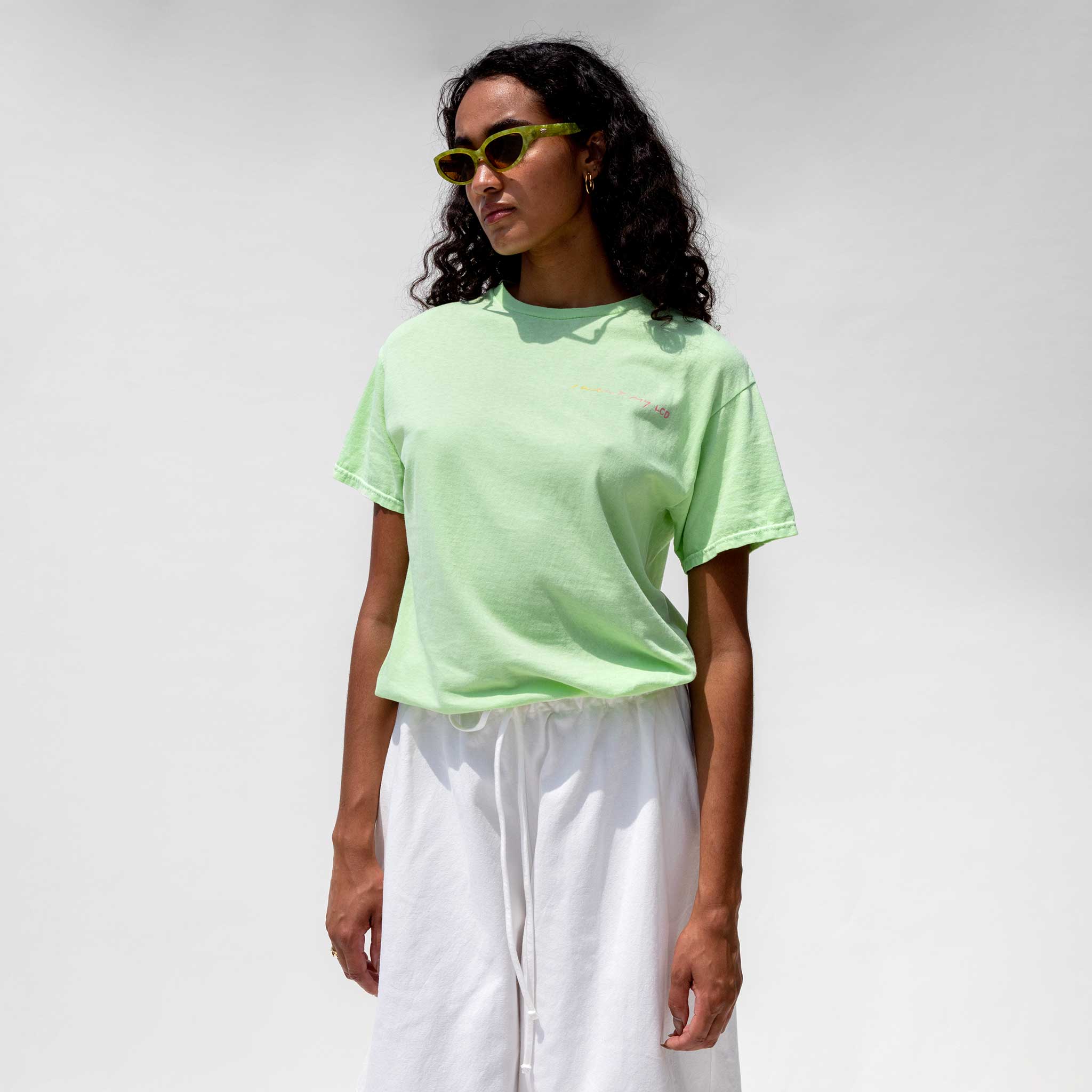 Half body photo of model wearing the Vintage Washed LCD10 Short Sleeve Motto Tee - Green. 