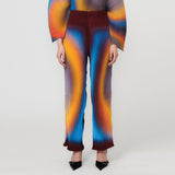A model wears the pleated Julie Heuer Jack Trousers with a multicolored aura-style graphic print.