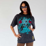 Front view of a model wearing the faded black Juicy Loaded graphic tee with blue graphic lettering and rhinestone embellishments.