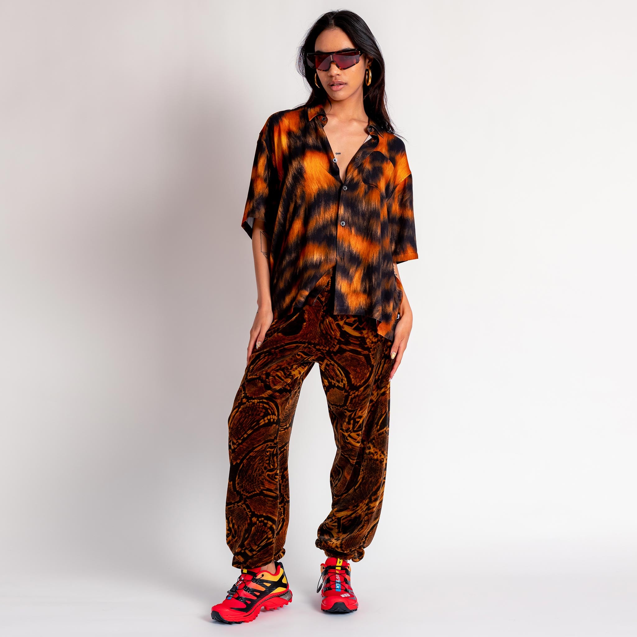 A model wears the Aries x Juicy Couture Psysnake Velour Sweatpants, with a brown and black snake print.