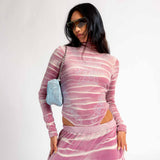 Front view of a model wearing the pink and white tie dyed velour Juicy long sleeve turtleneck bodysuit with rhinestone embellishments.