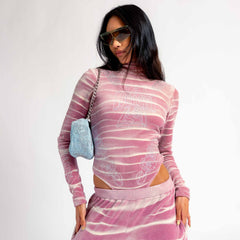 Front view of a model wearing the pink and white tie dyed velour Juicy long sleeve turtleneck bodysuit with rhinestone embellishments.