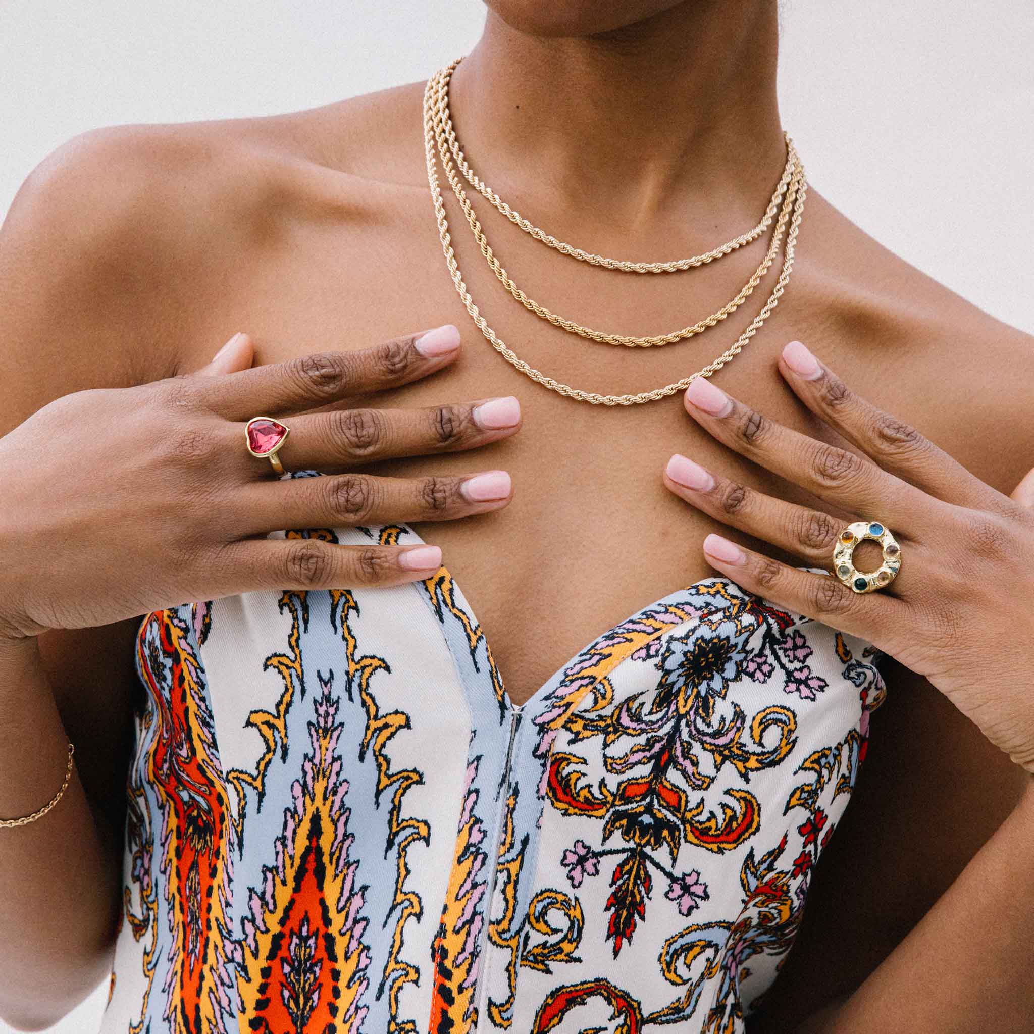 Detail photo of models hand placed on chest wearing the lovely ring in the color rose.