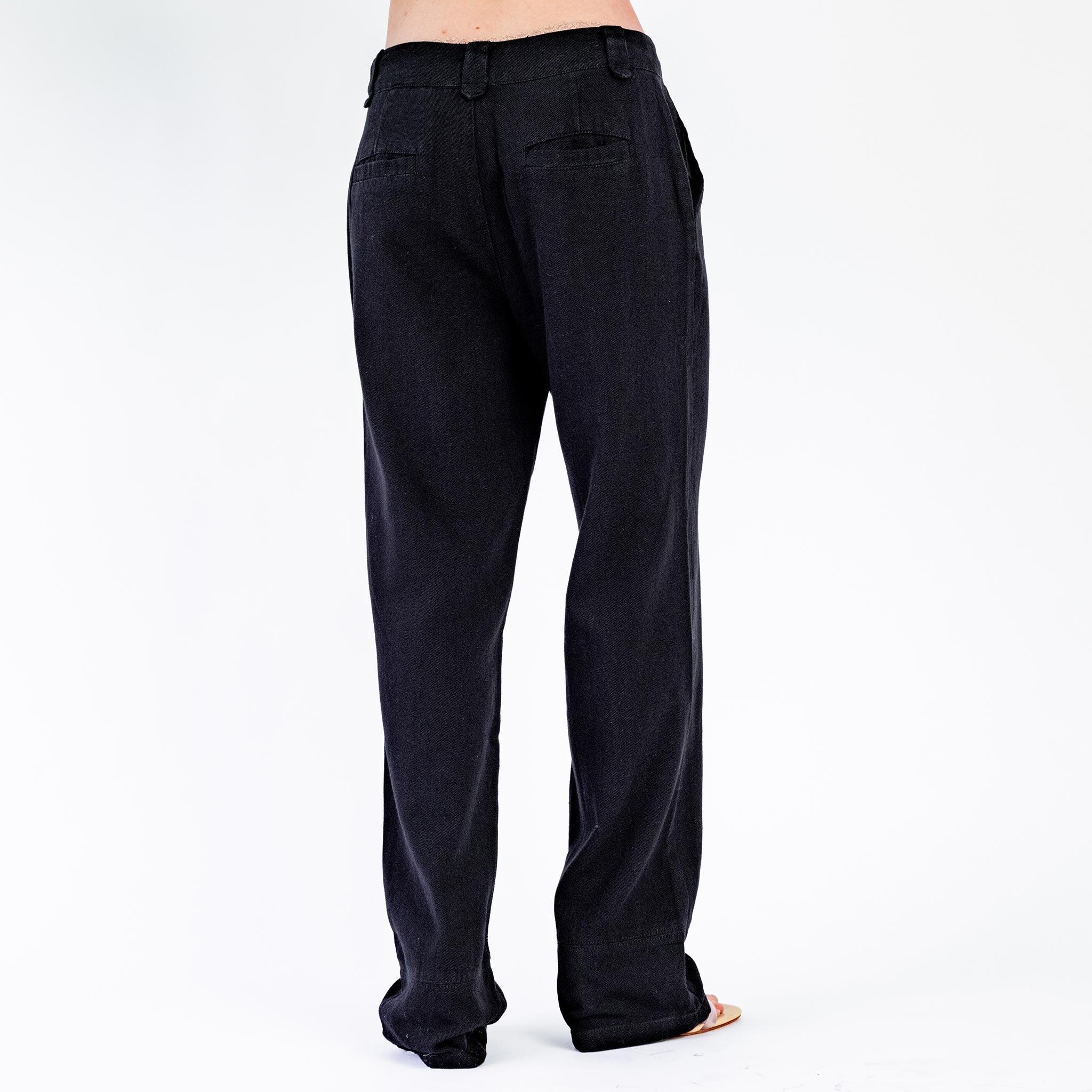 Back half body photo of model wearing the Low Rise Oversized Trousers - Black. 