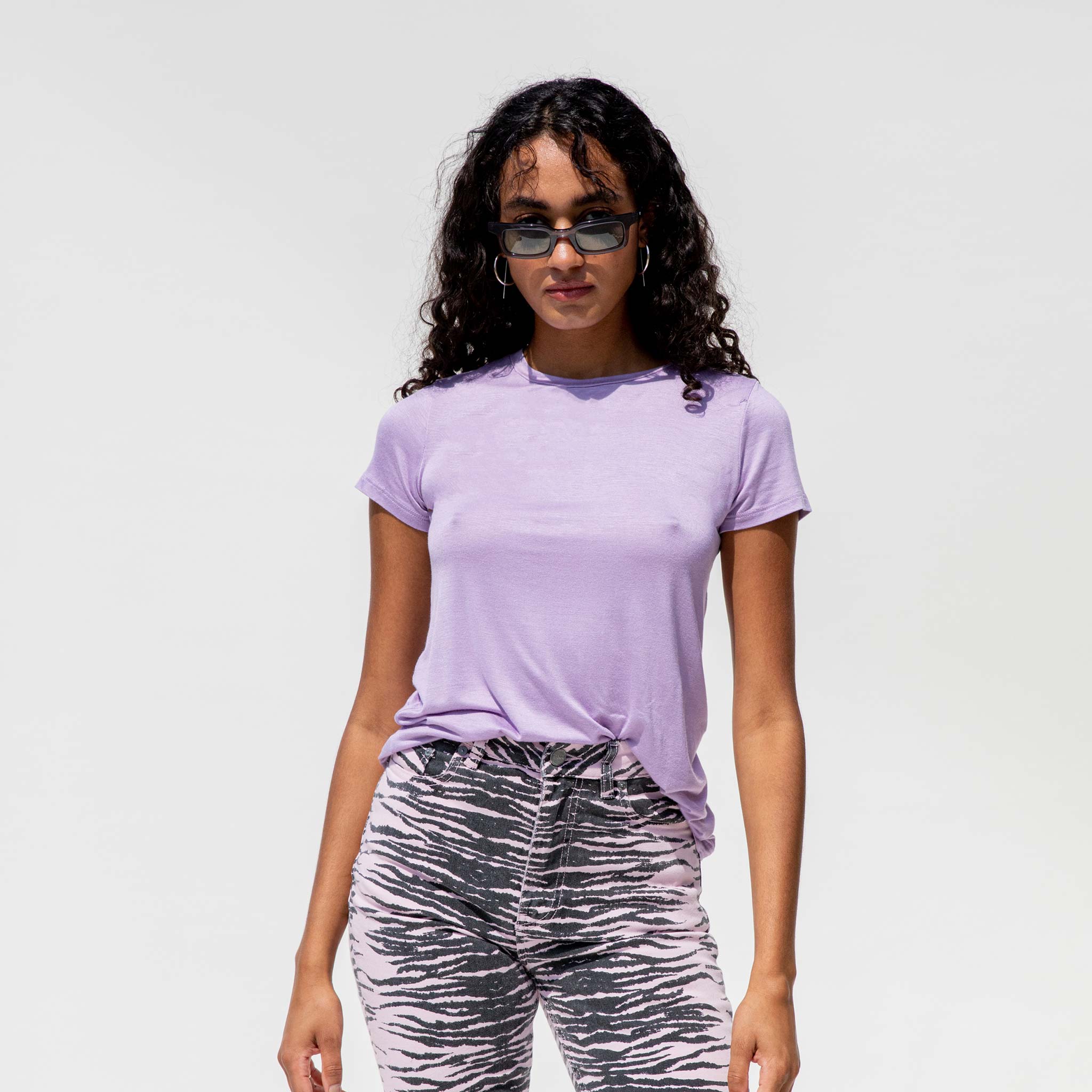 A model wears the lavender Modal Tee, paired with zebra print pink jeans.