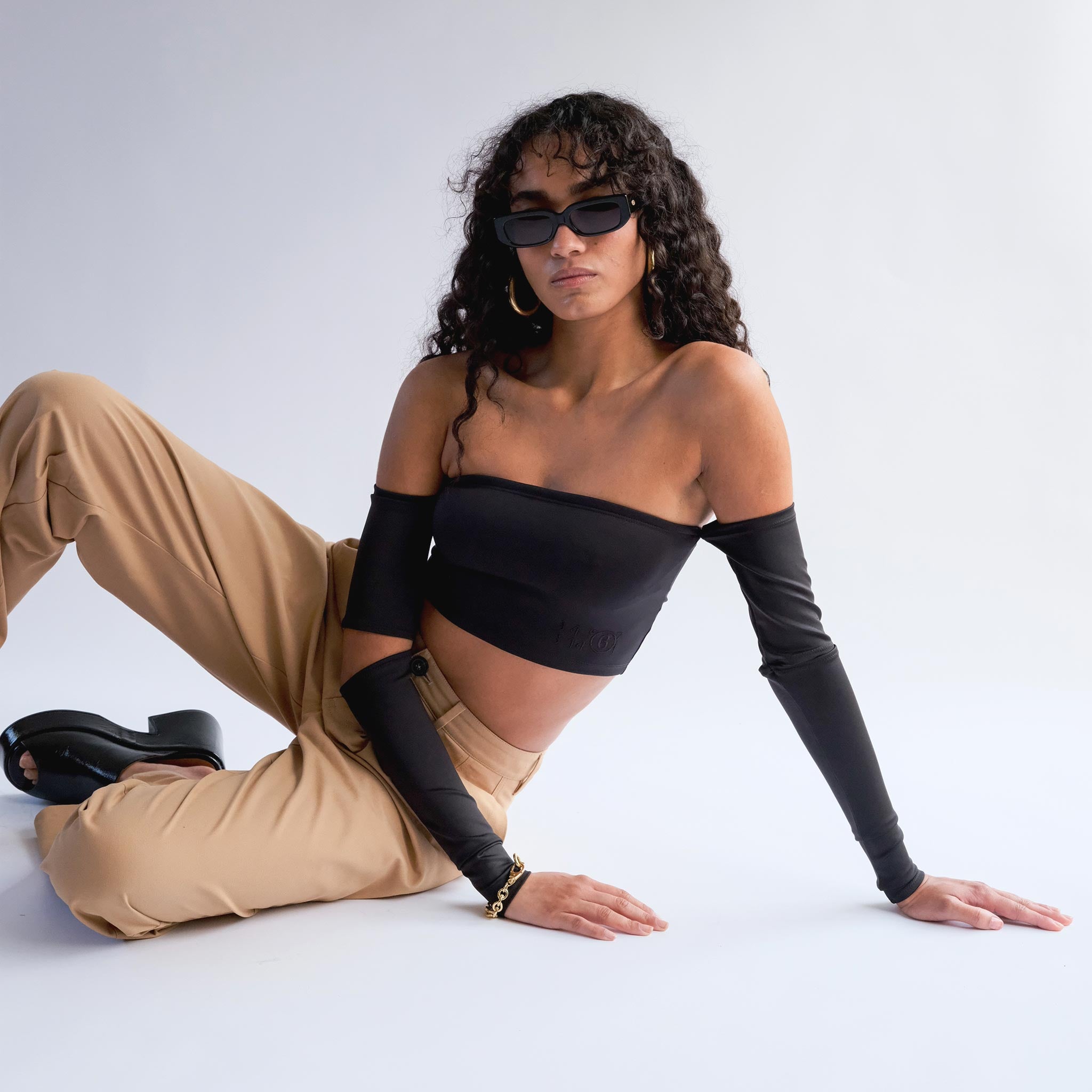 Full body photo of model sitting on the ground wearing the Off Shoulder Top with Sleeves - Black.