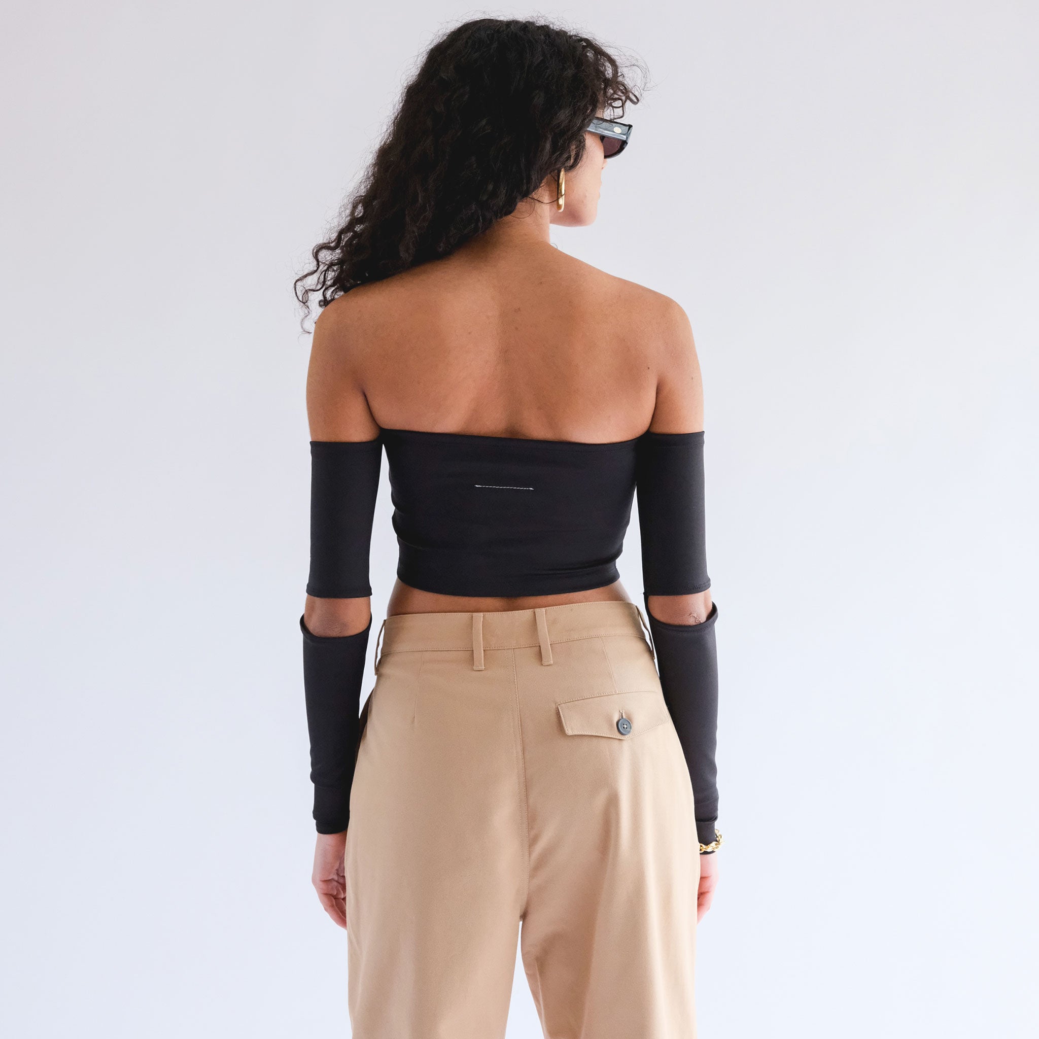 Back half body photo of model wearing the Full body photo of model sitting on the ground wearing the Off Shoulder Top with Sleeves - Black.